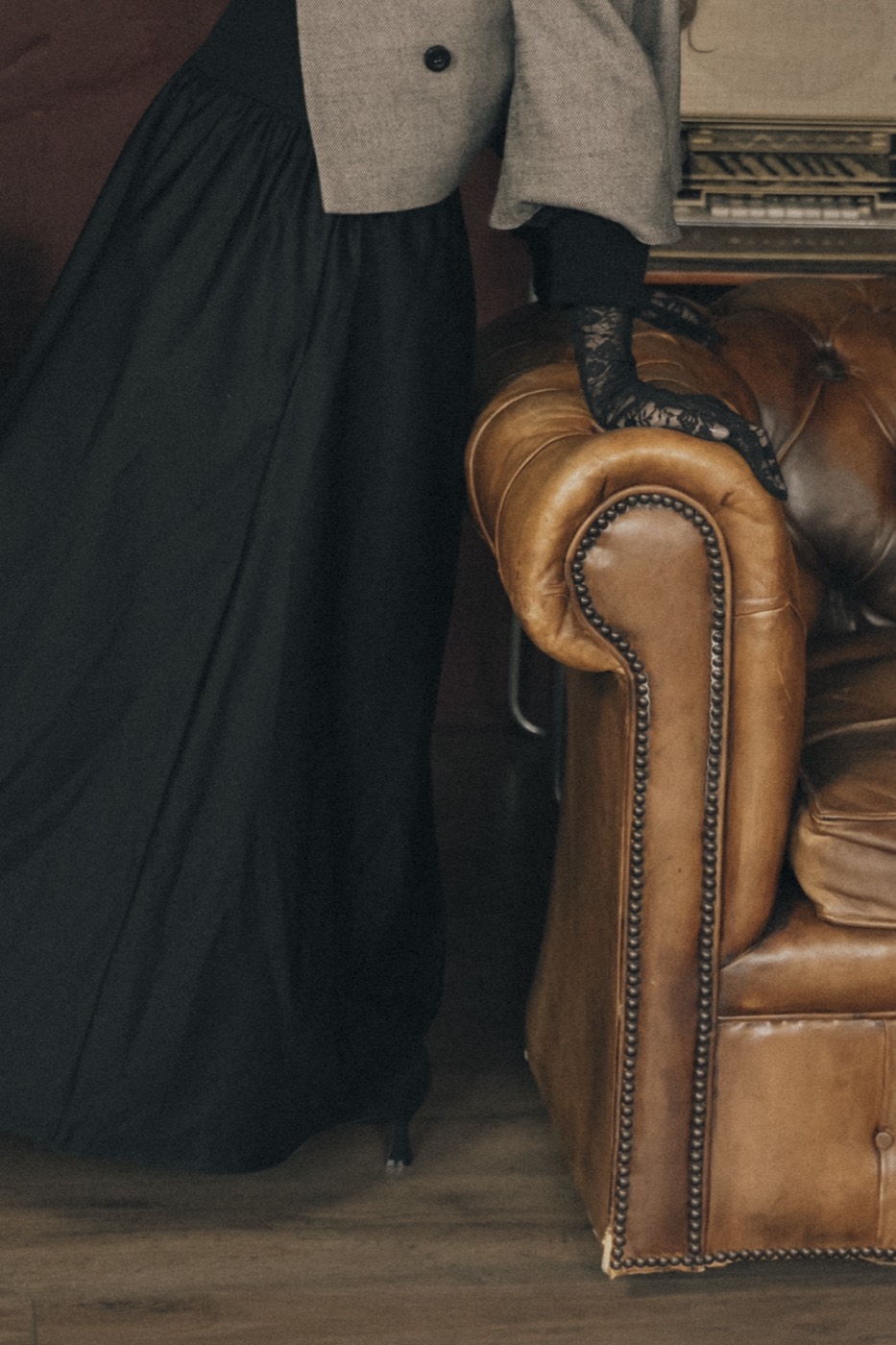 Detail van een zwarte jurk naast een vintage leren fauteuil