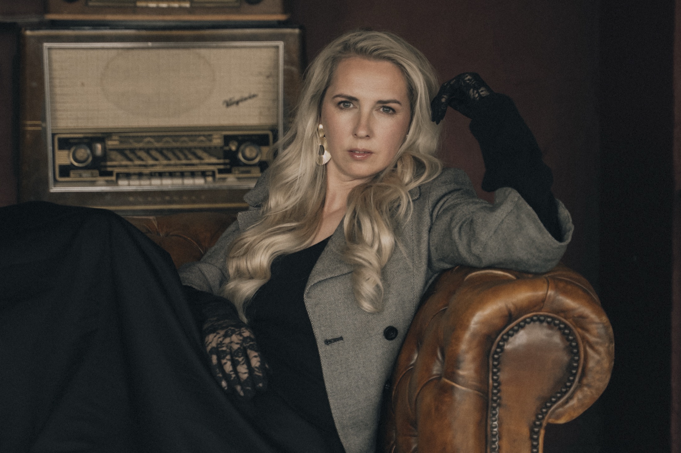 Talitha in een vintage leren stoel, met een oude radio op de achtergrond