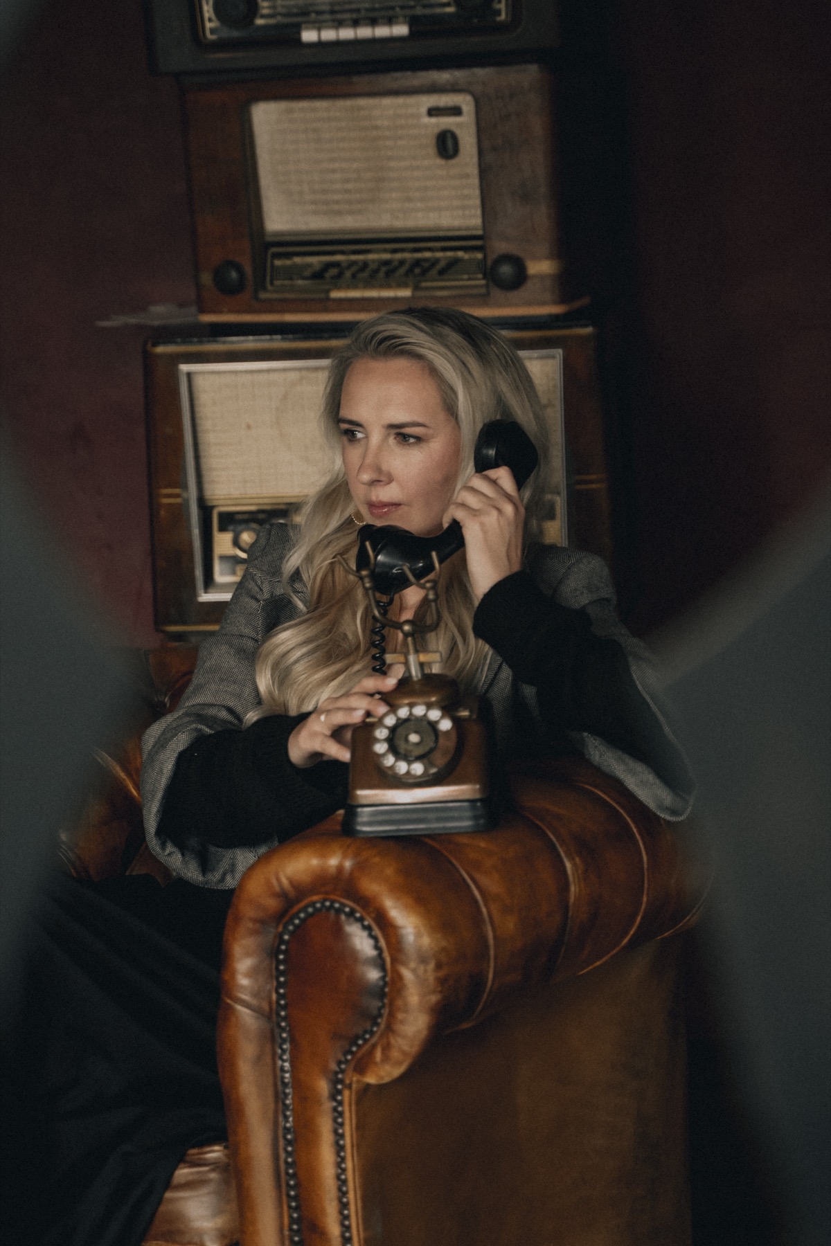 Talitha aan een vintage telefoon, tussen oude radio's